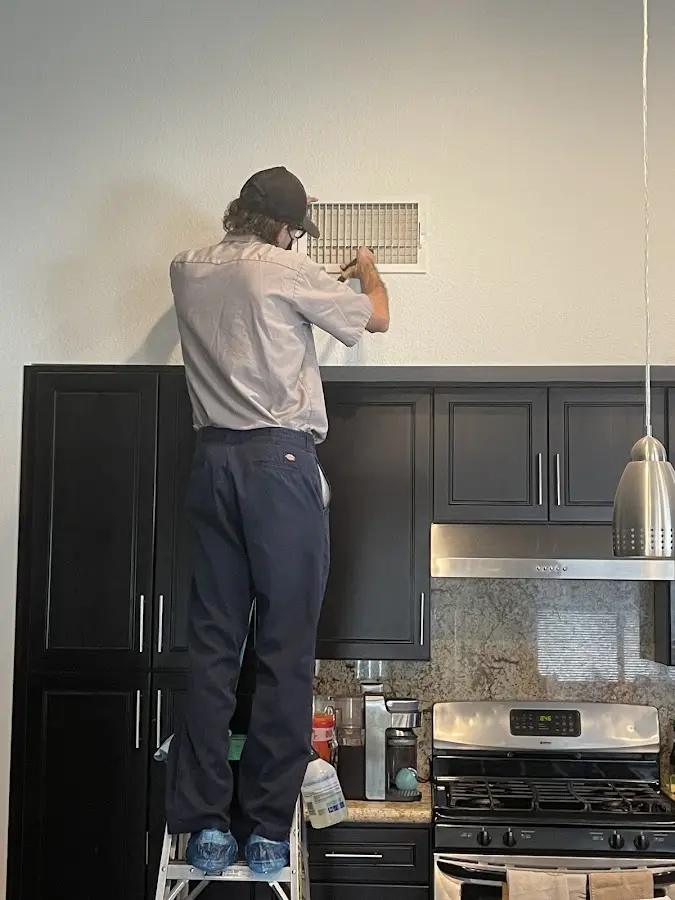 Technician inspecting an air vent during HVAC service in Orland
